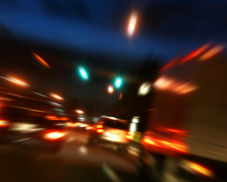 An image of cars on a nighttime highway, with blurred motion and bright lights.