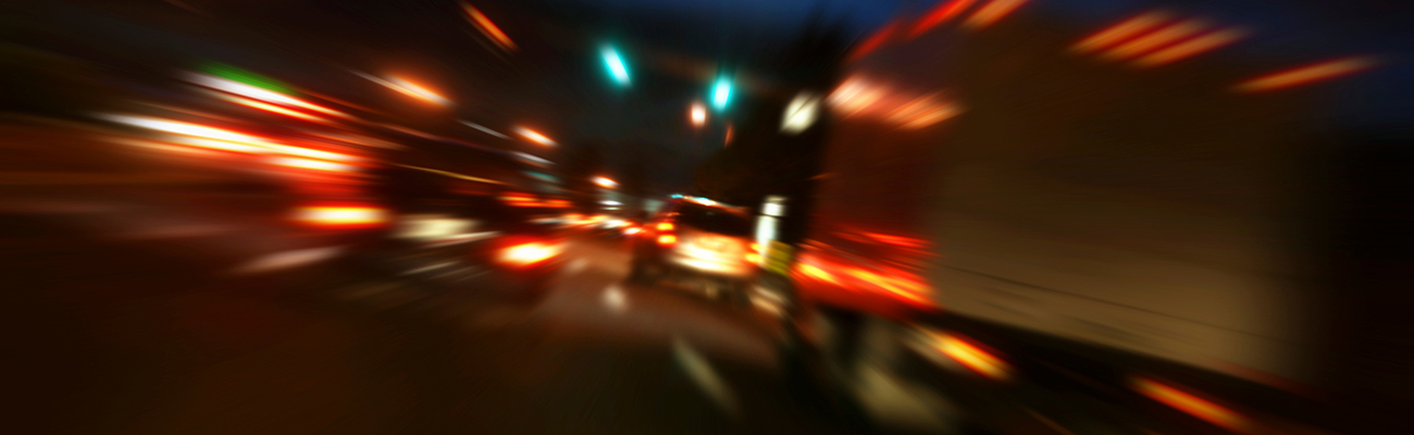 An image of cars on a nighttime highway, with blurred motion and bright lights.